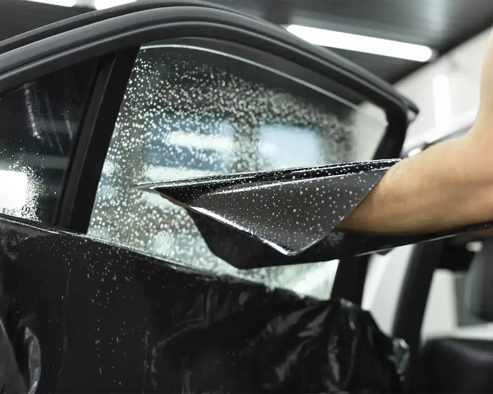 homem aplicando insufilm da marca sublime blue em janela de carro